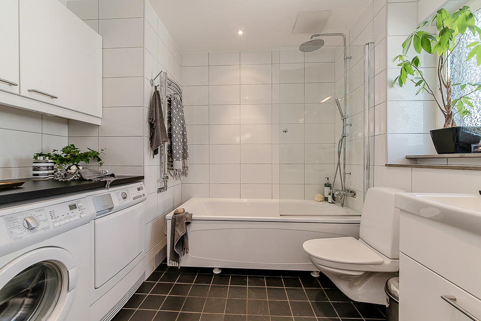 Stilfullt och genomtänkt badrum med badkar, tvättmaskin och torktumlare