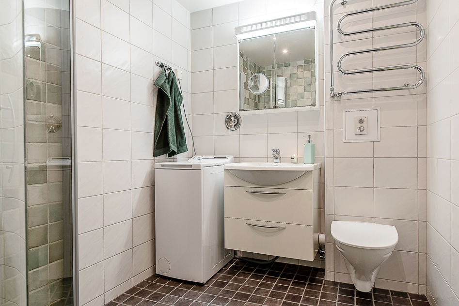 Fint badrum med duschhörna och tvättmaskin